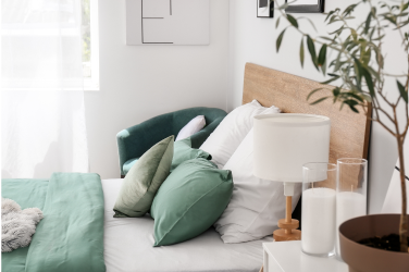 a bed with white covers and teal sheets against a wall taken from the side